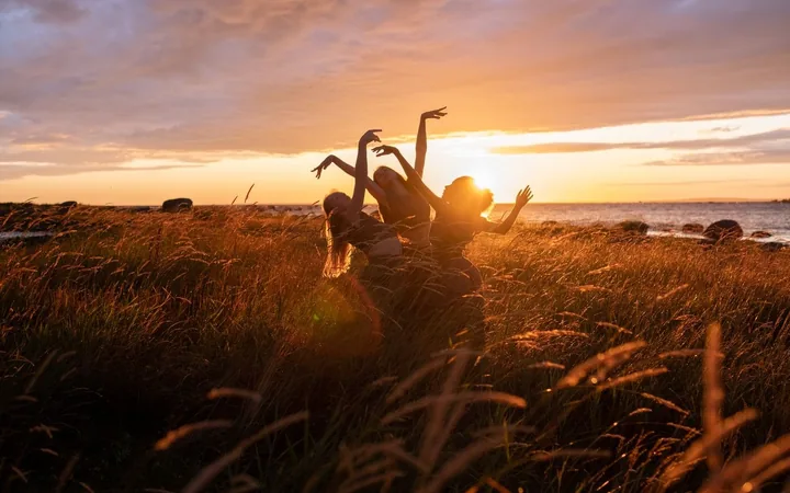 Two friends with their arms up at sunset